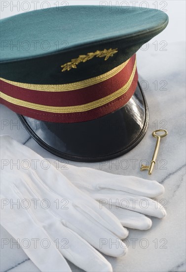 Doorman’s hat, gloves and key on table.