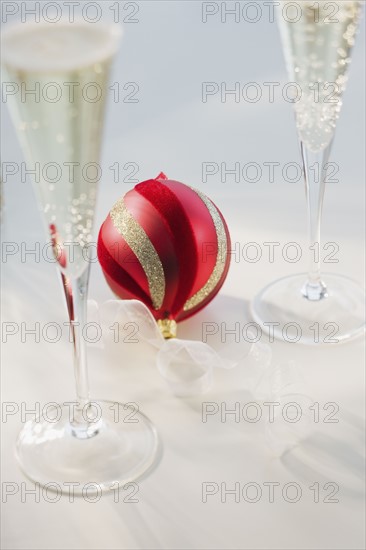 Christmas ornament next to champagne glasses.