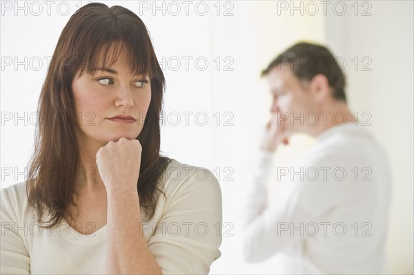 Upset woman with husband in background.