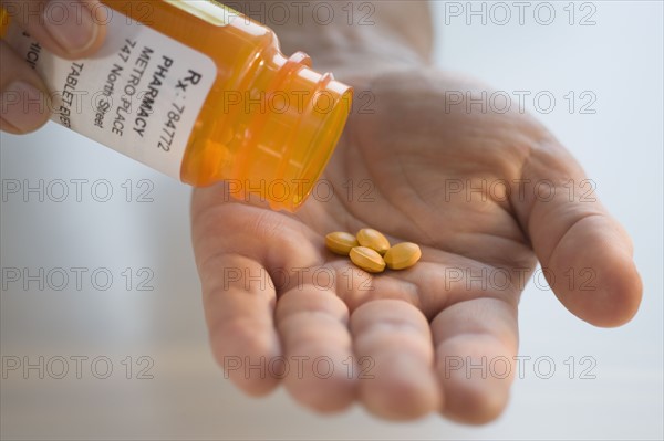 Man pouring prescription medication into hand.