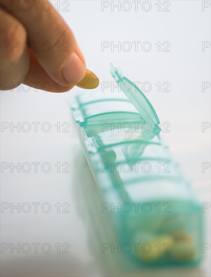 Man reaching for medication in pill organizer.