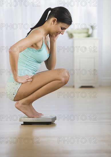 Woman crouching on scale.