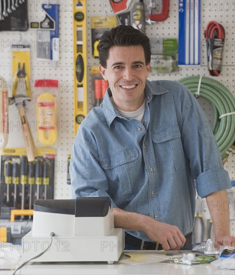 Sales clerk behind counter at hardware store.