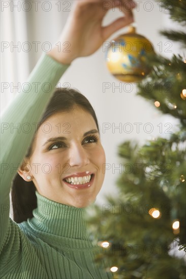 Woman hanging ornament on Christmas tree.