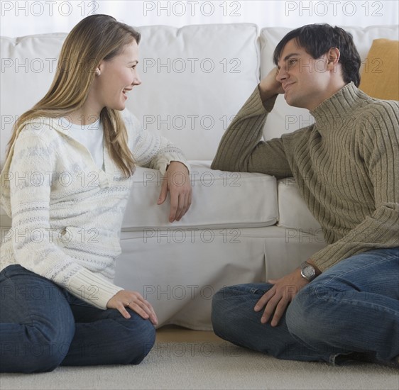 Couple sitting on floor talking.