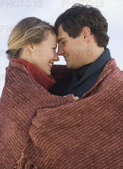 Couple wrapped in blanket.