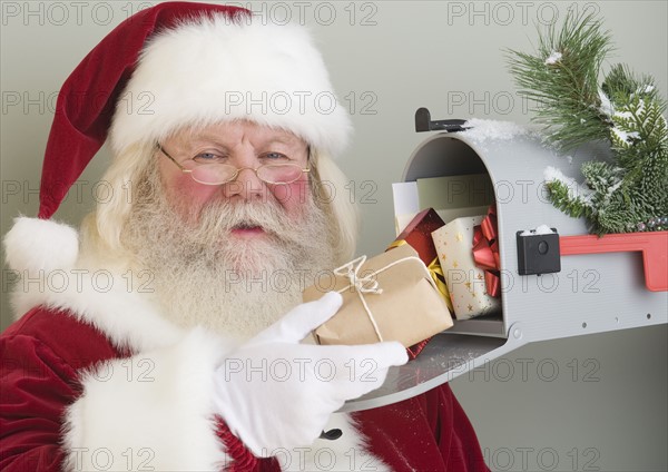 Santa Claus putting gifts in mailbox.