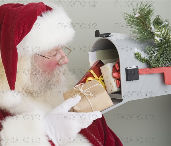 Santa Claus putting gifts in mailbox.