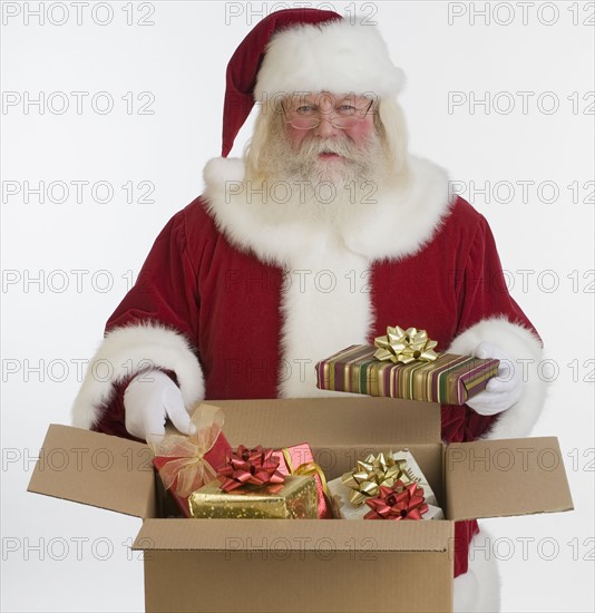 Santa Claus packing gifts in box.