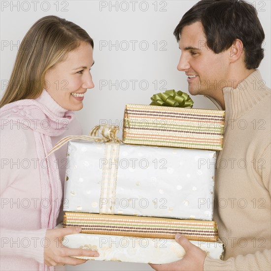 Couple holding pile of gifts.