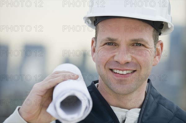 Male construction worker holding blueprints.