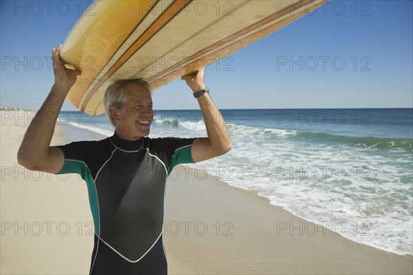 Man holding surfboard at beach.