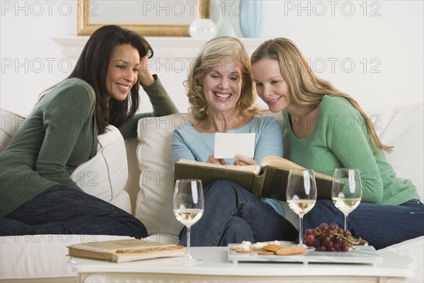 Multi-ethnic women looking at photo album.