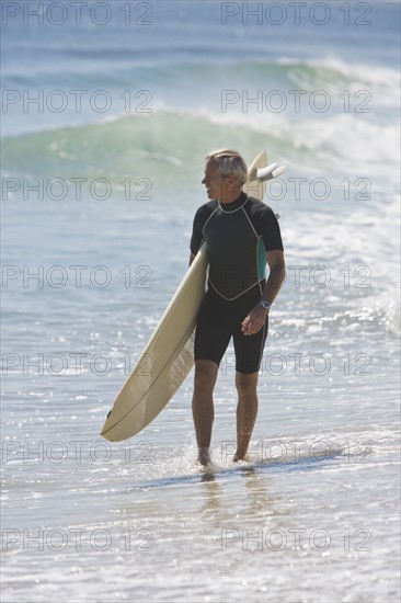 Man carrying surfboard at beach.