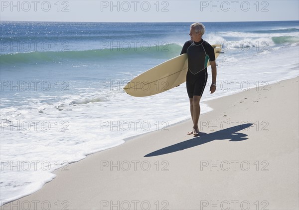 Man carrying surfboard at beach.