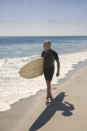 Man carrying surfboard at beach.