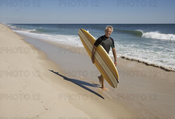 Man carrying surfboard at beach.