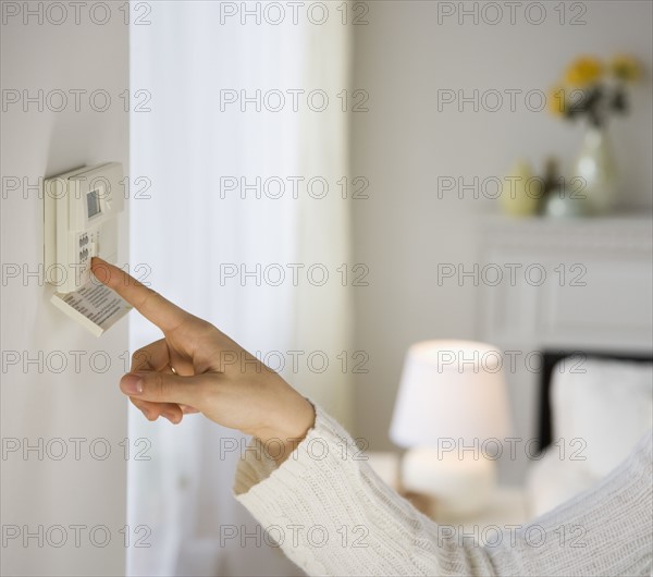 Woman adjusting digital thermostat.