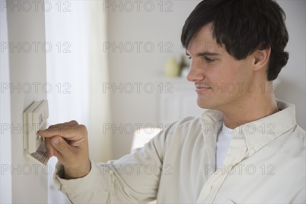 Man adjusting digital thermostat.
