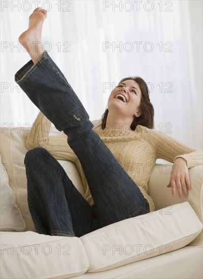 Woman kicking leg on sofa.