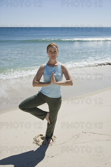 Woman practicing yoga at beach.