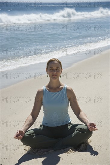 Woman practicing yoga at beach.