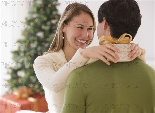 Woman holding gift and hugging husband.