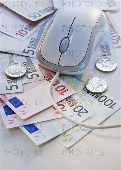 Computer mouse on euro banknotes and coins.