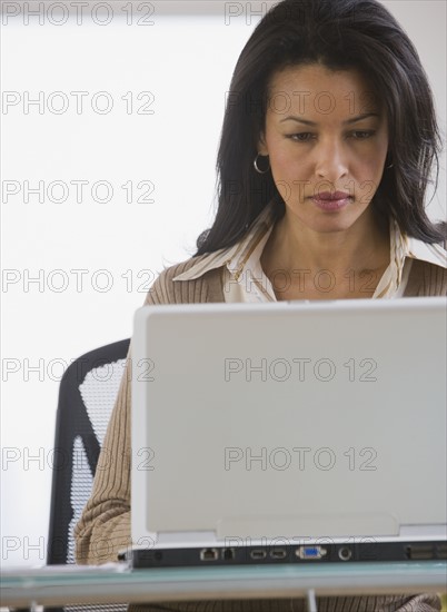 African businesswoman looking at laptop.