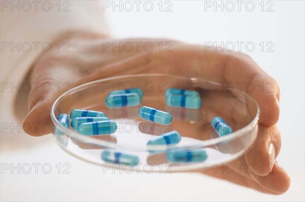 Man holding prescription medication in Petri dish.