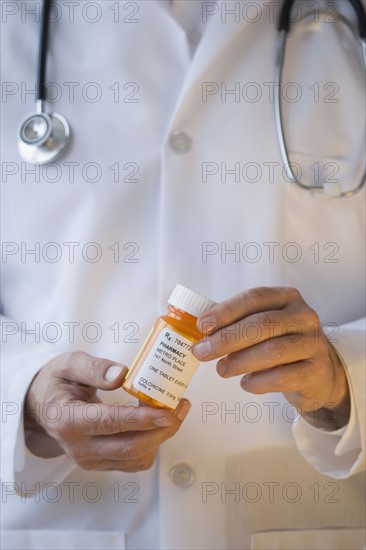 Doctor holding prescription bottle.