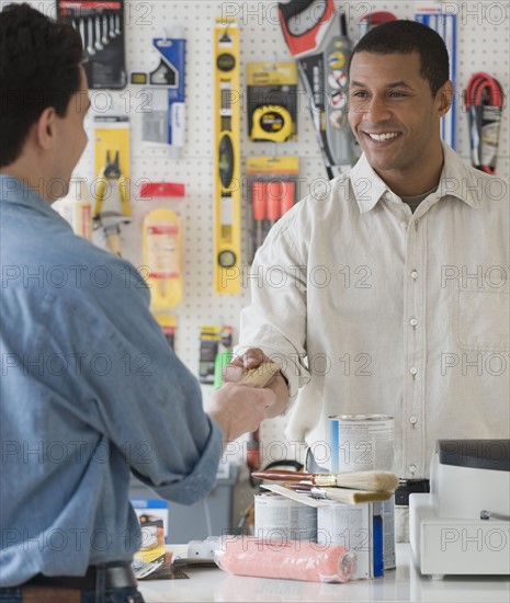 African sales clerk at hardware store handing over credit card.