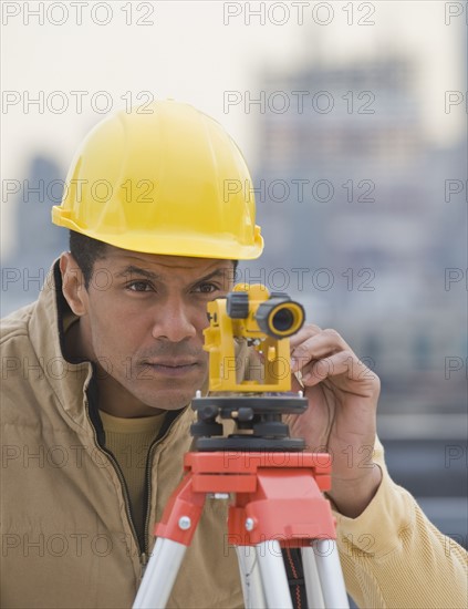 African male surveyor looking through measuring device.