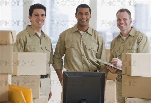 Multi-ethnic delivery men next to computer.