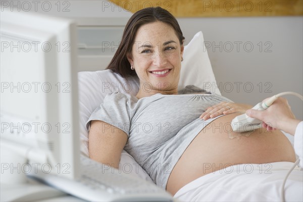 Pregnant Hispanic woman looking at ultrasound monitor.