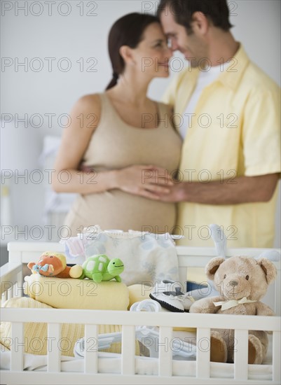 Pregnant Hispanic couple hugging.