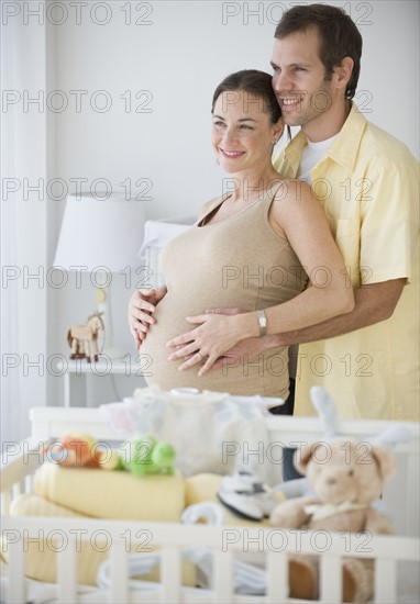 Pregnant Hispanic couple hugging.