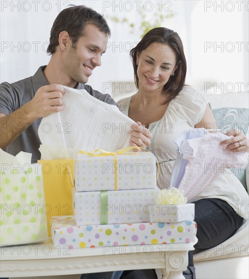 Pregnant Hispanic couple opening gifts.