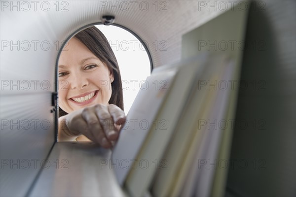 Woman reaching into mailbox for mail.