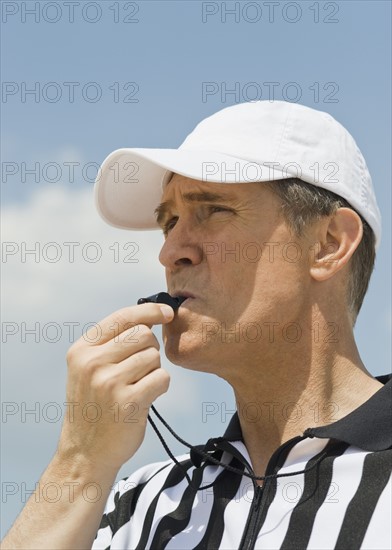 Male referee blowing whistle.