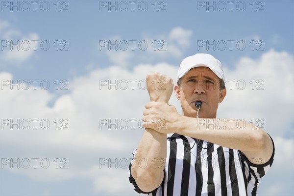 Male football referee making holding call.