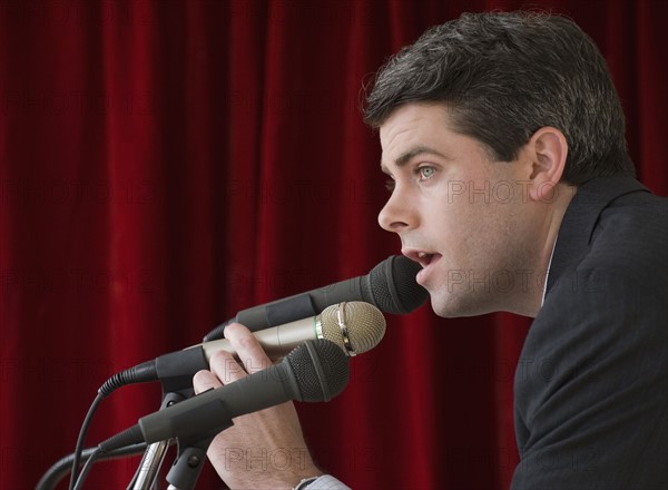 Businessman speaking into microphone.