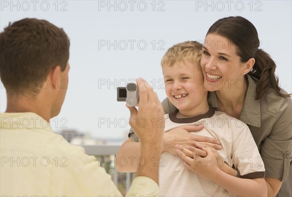 Father video recording wife and son.