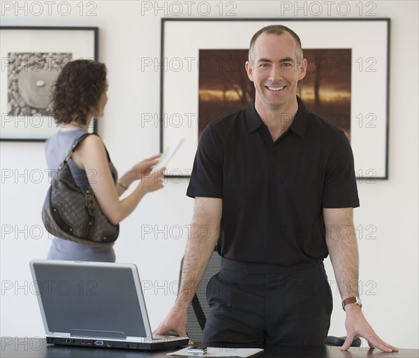 Businessman leaning on desk.