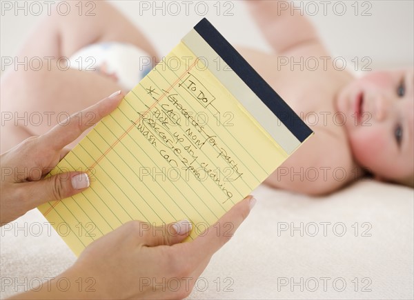 Mother looking at To Do list in front of baby. Date : 2008
