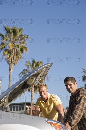 Two men looking under car hood. Date : 2008