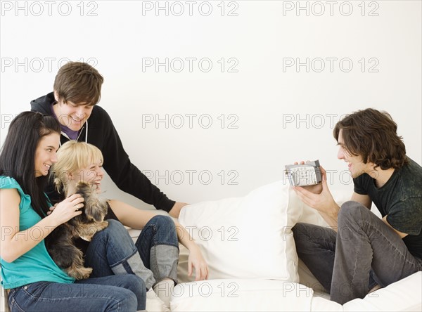 Man video recording friends on sofa. Date : 2008