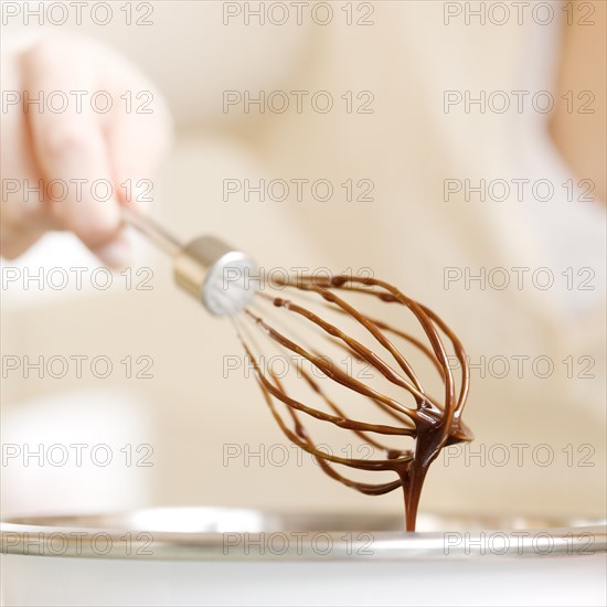 Woman holding whisk with chocolate batter. Date : 2008