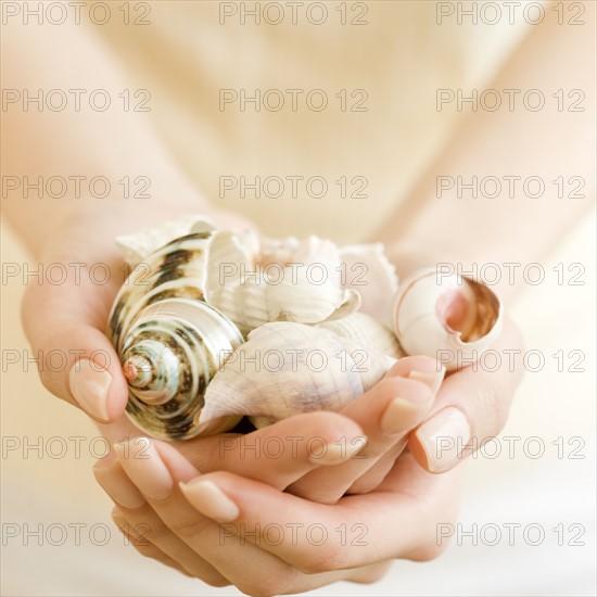 Woman holding handful of seashells. Date : 2008