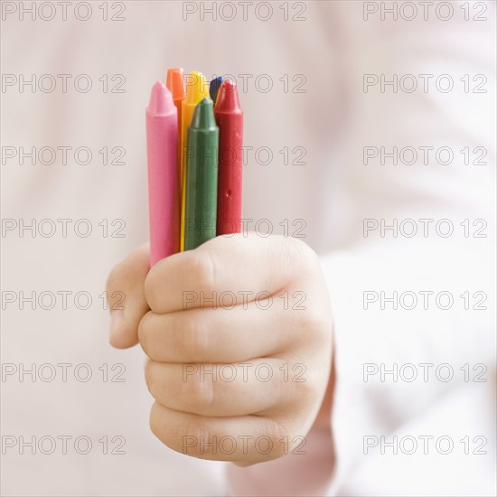 Child holding assorted crayons. Date : 2008